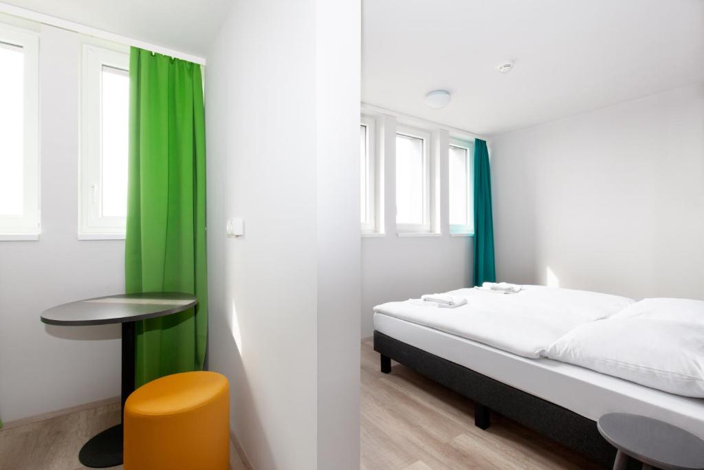 a bedroom with a bed and a table and green curtains at a&o Prague Rhea in Prague
