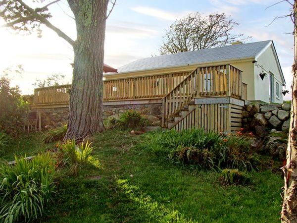 ein Holzhaus mit einem Baum im Hof in der Unterkunft 2 Clancy Cottages in Kilkieran