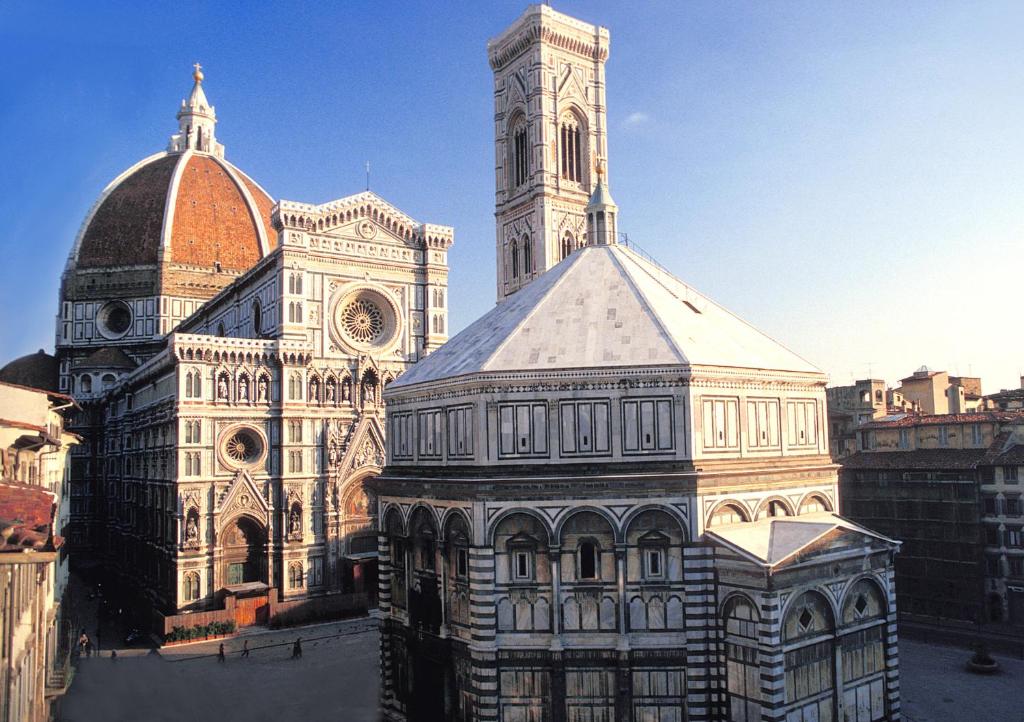 un grand bâtiment avec une tour et une église dans l'établissement Albergo San Giovanni, à Florence