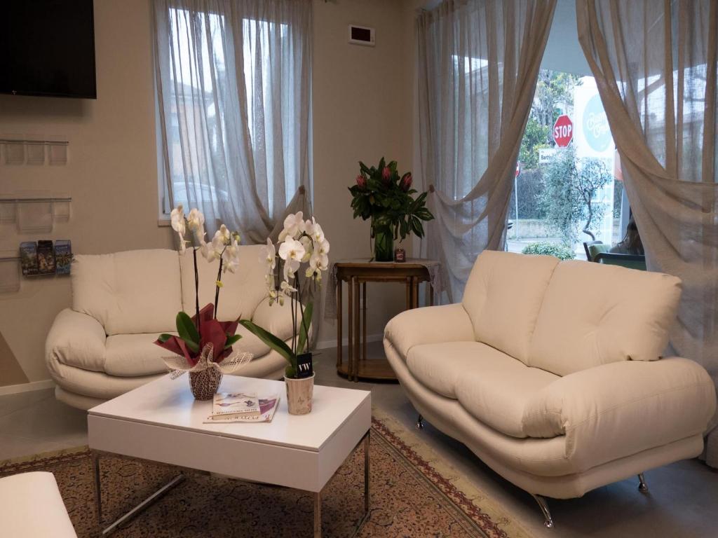 a living room with two white couches and a table at Hotel Buena Onda in Peschiera del Garda