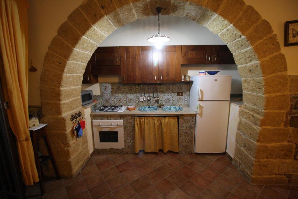una cocina con un arco de piedra con nevera en Casa Porto Salvo, en Cefalú