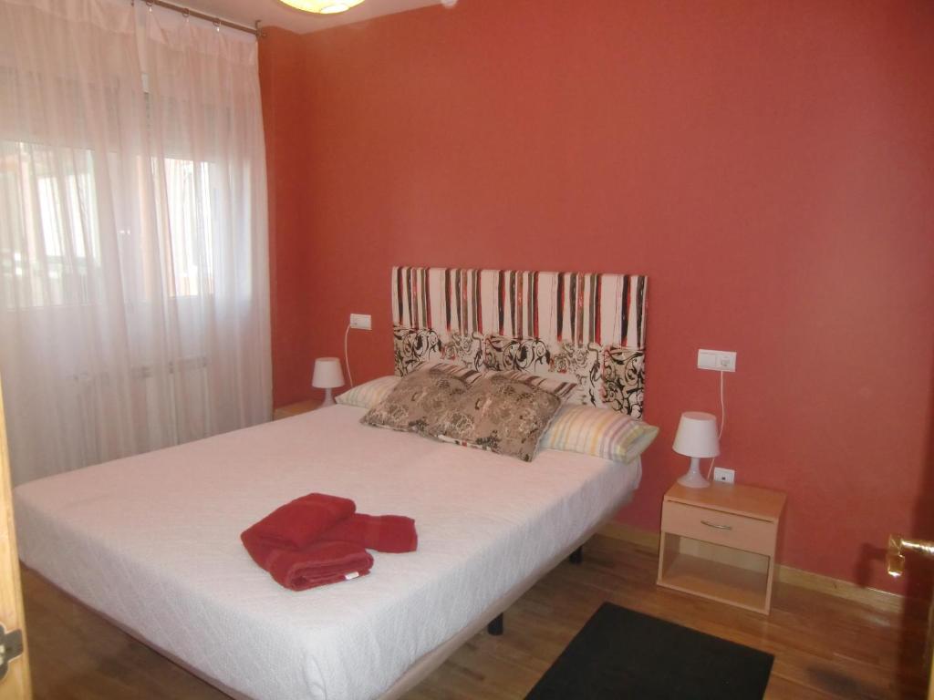 a bedroom with a large bed with red walls at Apartamento DH in Zamora