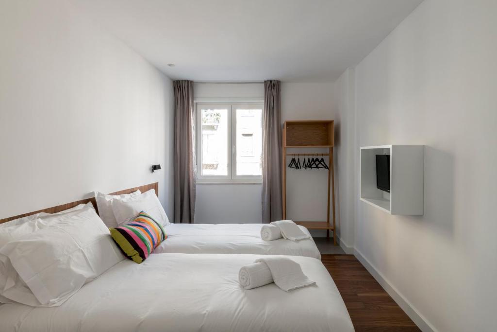 a bedroom with two beds and a tv on a wall at Lisbon Domus 74 by amcf in Lisbon
