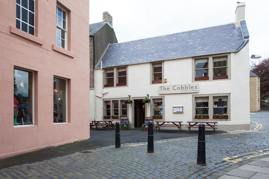 een wit gebouw met banken ervoor bij The Cobbles Inn Apartment in Kelso