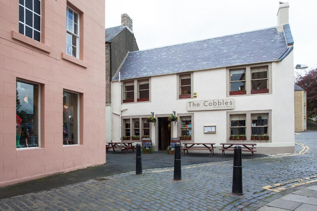 a white building with benches in front of it at The Cobbles Inn Apartment in Kelso