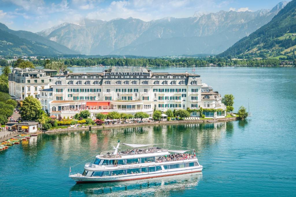 a boat in the water in front of a large building at Grand Hotel Zell am See in Zell am See