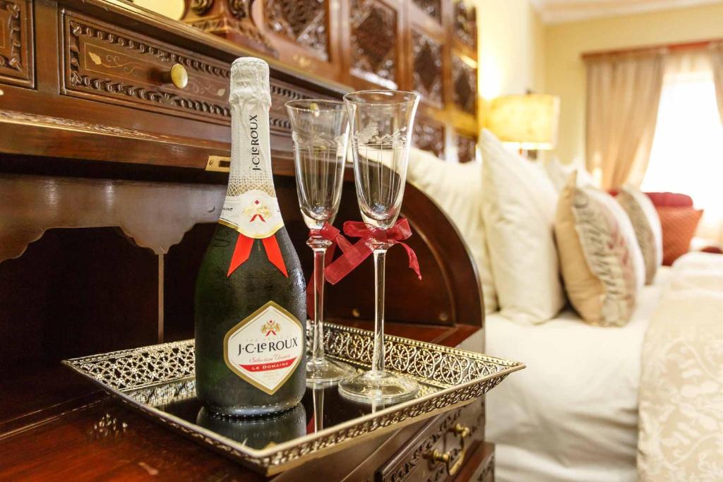 a bottle of champagne and two wine glasses on a table at Riverside Guest Lodge in Oudtshoorn