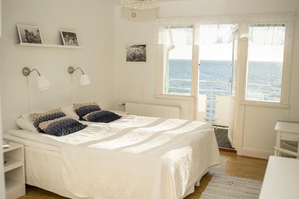 a white bedroom with a bed with a view of the ocean at Pensionat Strandgården in Mölle