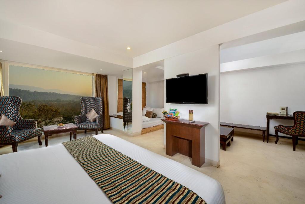 a hotel room with a bed and a flat screen tv at EllBee Ganga View in Rishīkesh