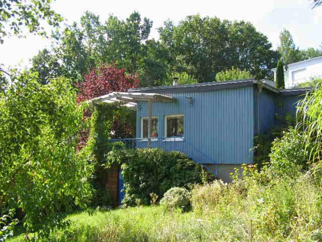 een blauw huis in het midden van een veld bij blaues Haus am See in Schwarz