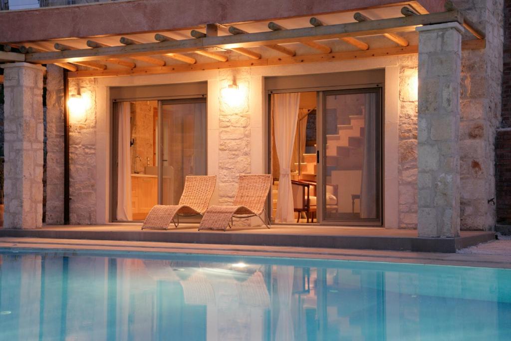 アギア・ペラギアにあるThomais Resort - 2 Villas with a Pool and Sea Viewのスイミングプールの横に座る椅子