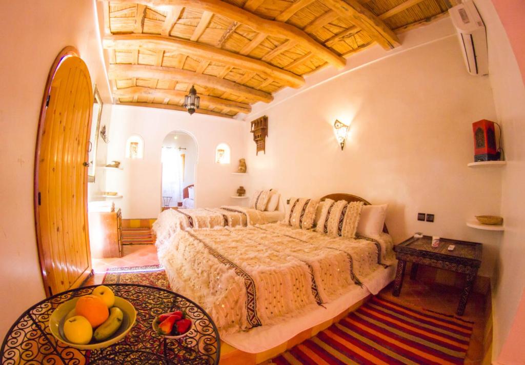 a bedroom with a bed and a table with fruits on it at Hotel Babylon Dades in Imdiazene