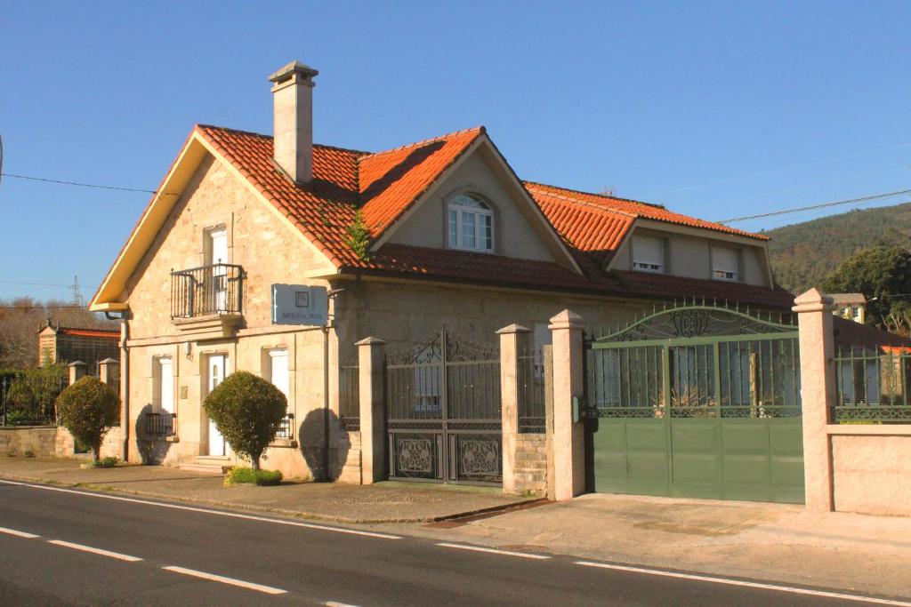 una casa con tetto arancione e garage verde di Casa rural agro da moa ad As Mirans