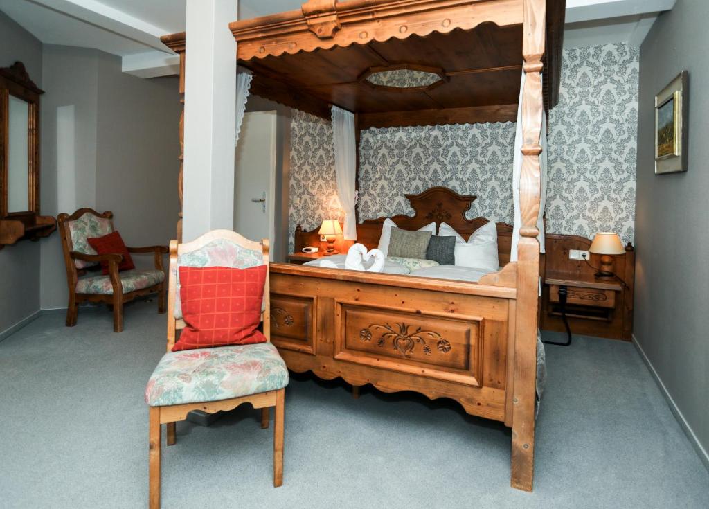 a bedroom with a wooden canopy bed with a chair at Marienthaler Gasthof in Marienthal