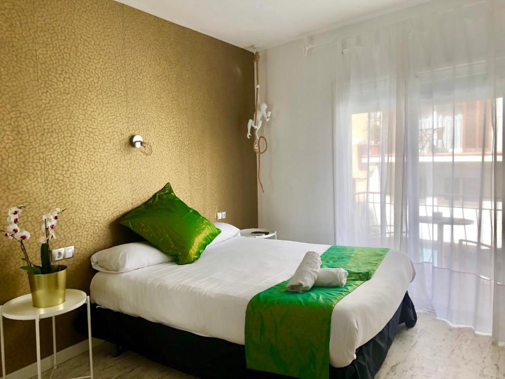 a bedroom with a bed with a green blanket and a window at Sitges Eleven in Sitges