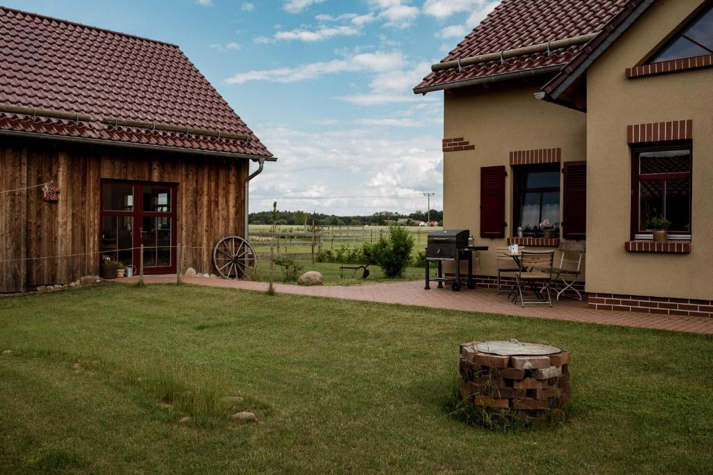 a backyard with a house and a yard with a grill at Südhof Döbbrick - Ferienhof für Familienurlaub in Cottbus