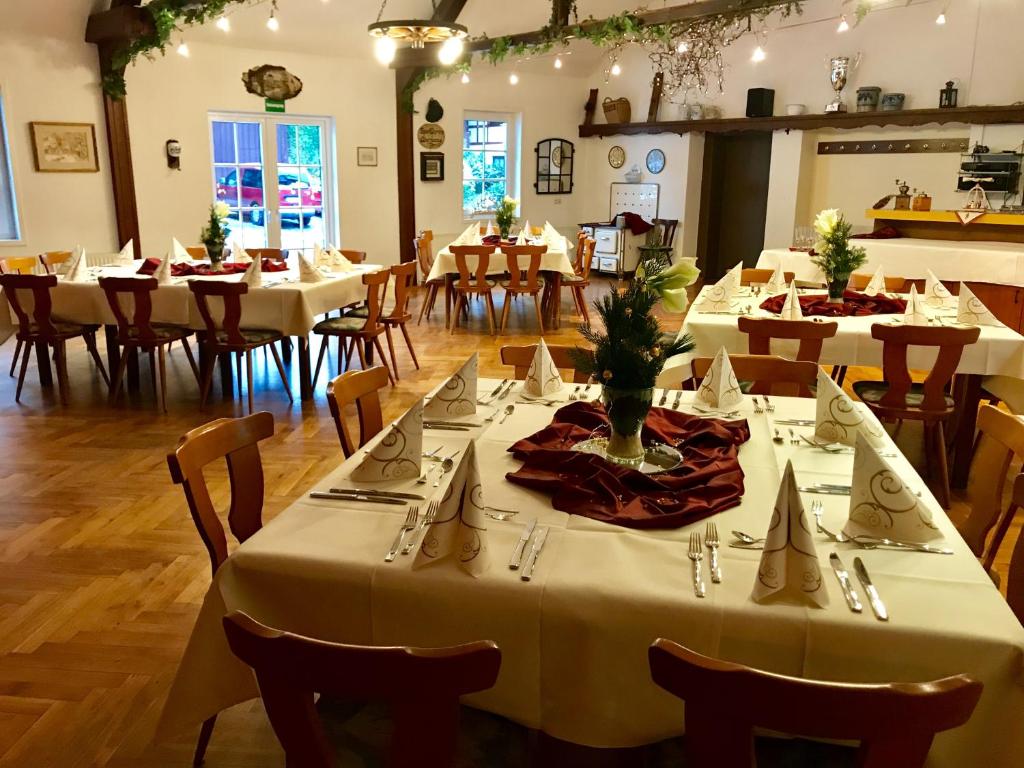 uma sala de jantar com mesas e cadeiras brancas em Landgasthof & Hotel Jossatal em Breitenbach am Herzberg