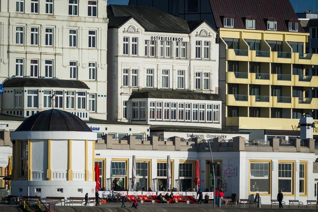 un grupo de edificios con gente caminando delante de ellos en Strandhotel Ostfriesenhof en Borkum