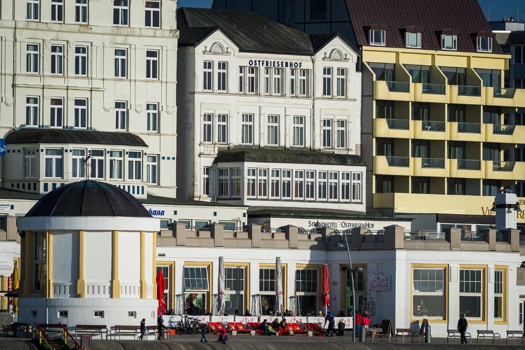 um grupo de edifícios com pessoas andando na frente deles em Strandhotel Ostfriesenhof em Borkum