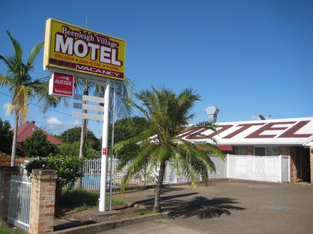 Beenleigh Village Motel في بينلبيه: علامة موتيل أمام مبنى فيه نخلة