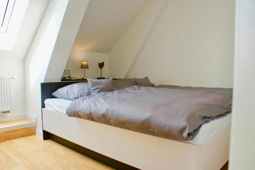 a white bedroom with a bed in a attic at Deichhotel Rose in Juist