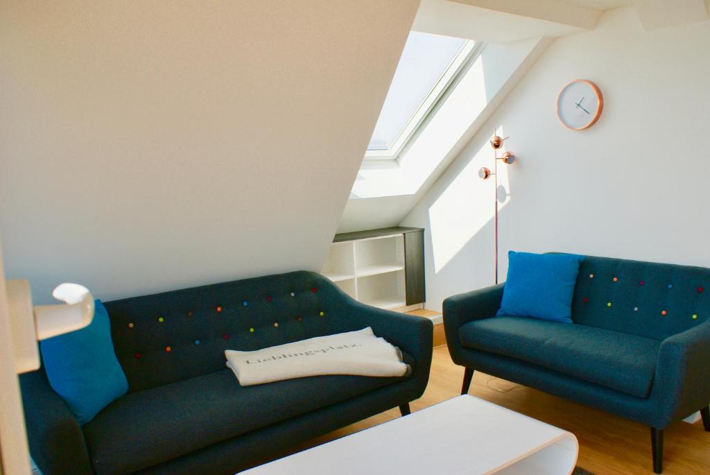 a living room with two blue couches and a clock at Deichhotel Rose in Juist