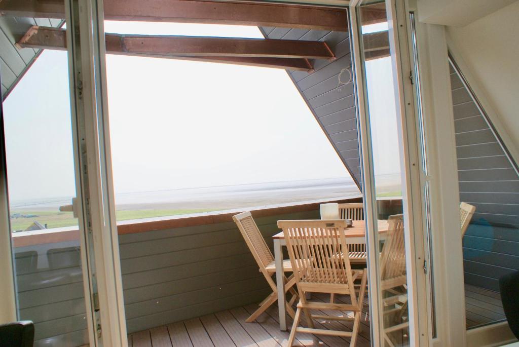 a balcony with a table and chairs and a window at Deichhotel Rose in Juist