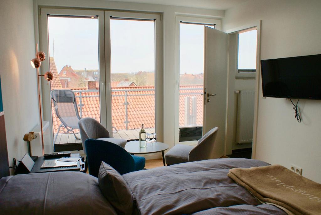 a bedroom with a bed and a view of a balcony at Deichhotel Rose in Juist