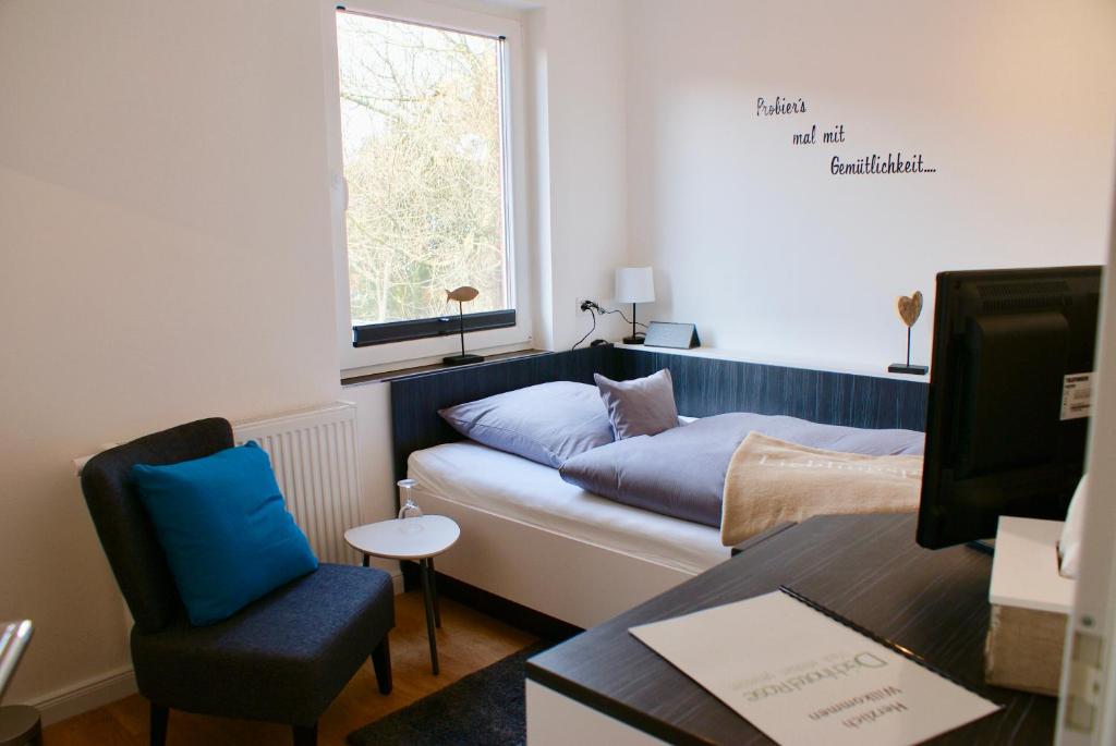 a room with a bed and a chair and a table at Deichhotel Rose in Juist