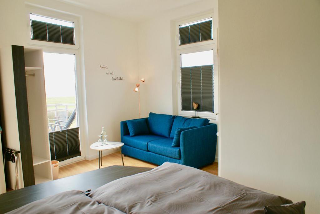 a bedroom with a blue couch and windows at Deichhotel Rose in Juist