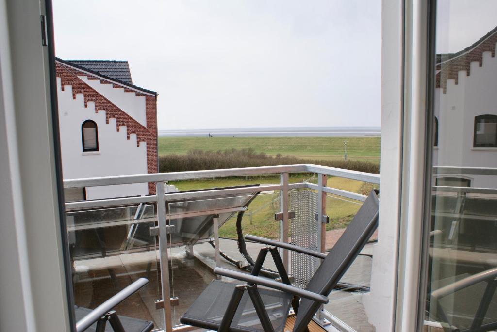 a balcony with a chair and a view of a field at Deichhotel Rose in Juist