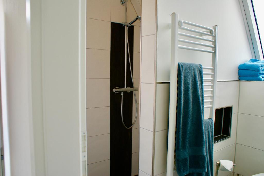 a shower in a bathroom with a mirror at Deichhotel Rose in Juist