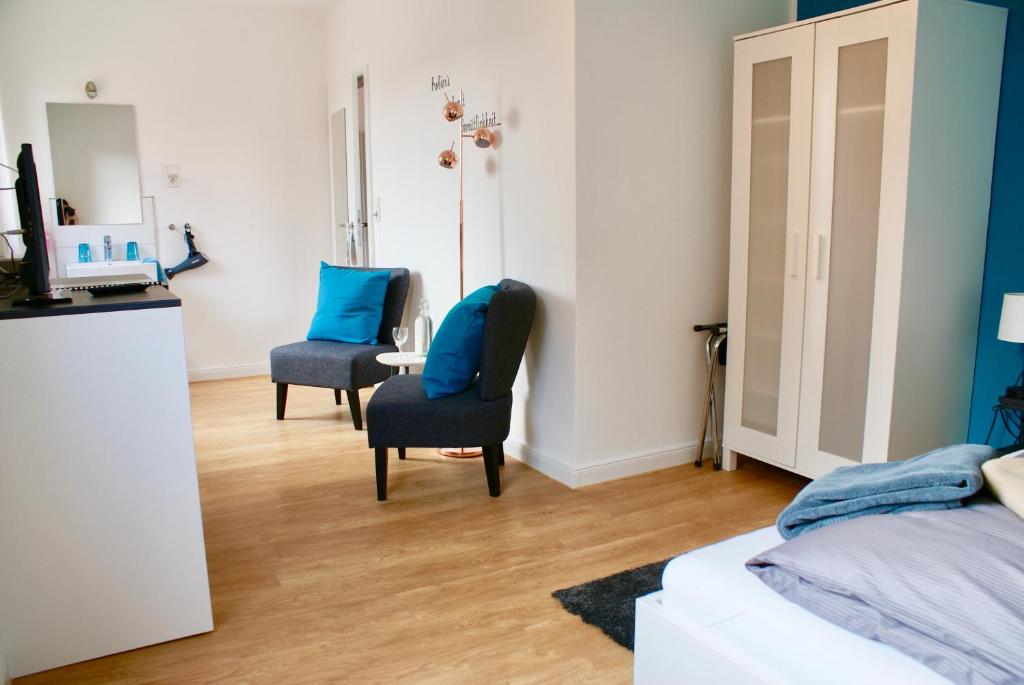 a bedroom with two chairs and a bed and a mirror at Deichhotel Rose in Juist