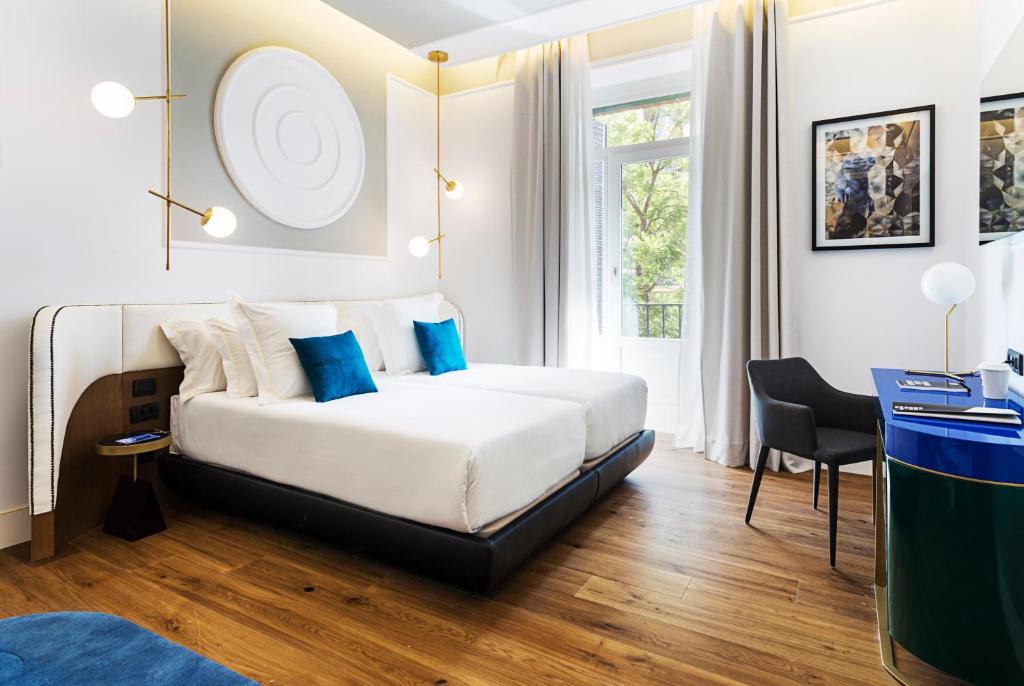 Habitación de hotel con cama con almohadas azules en One Shot Fortuny 07 en Madrid