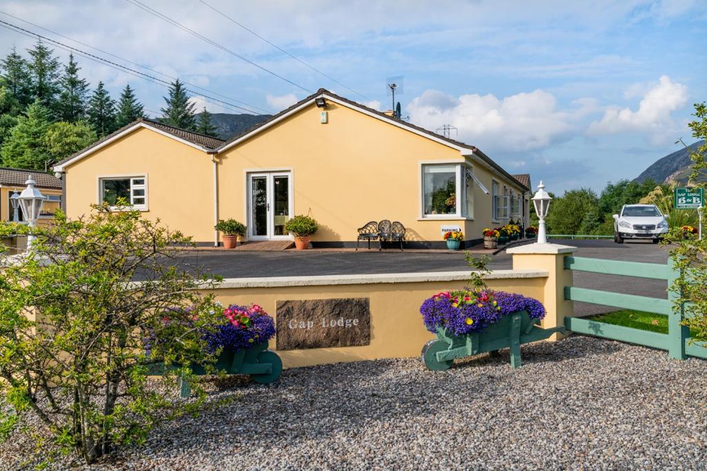 een geel huis met bloemen ervoor bij The Gap Lodge B&B in Donegal