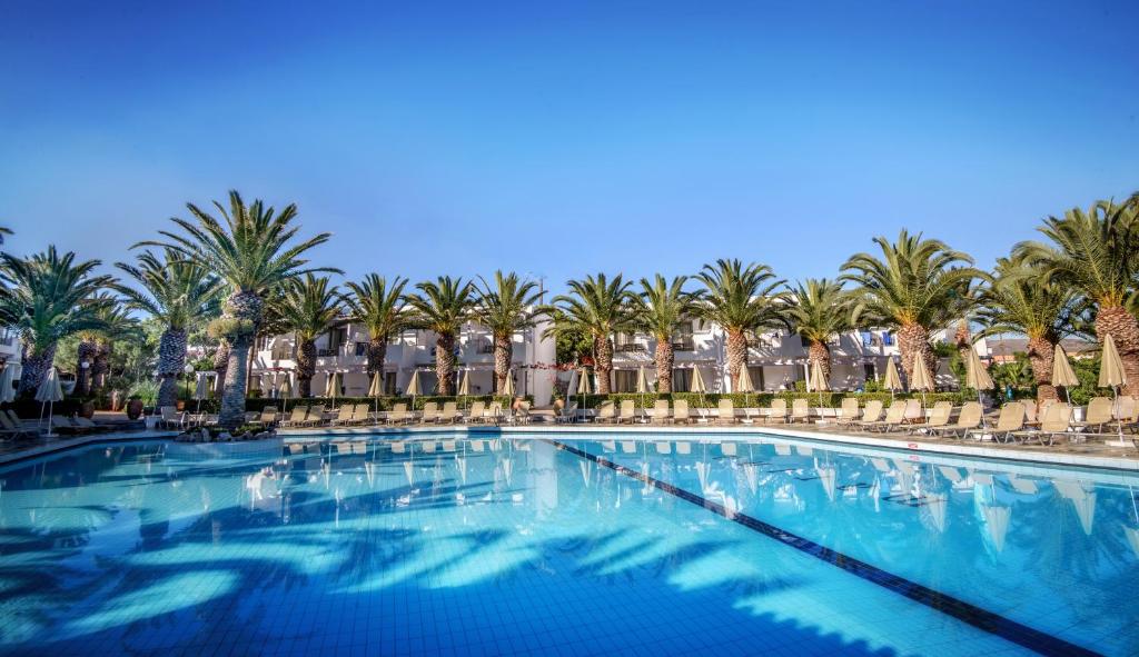 a large swimming pool with palm trees in the background at Sol Marina Beach Crete in Gouves
