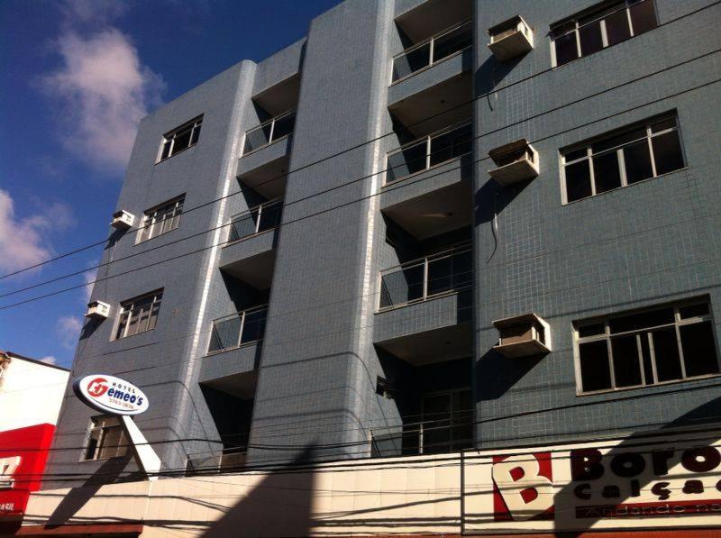 um edifício alto e cinzento com uma placa à frente. em Hotel Gemeos em São Mateus