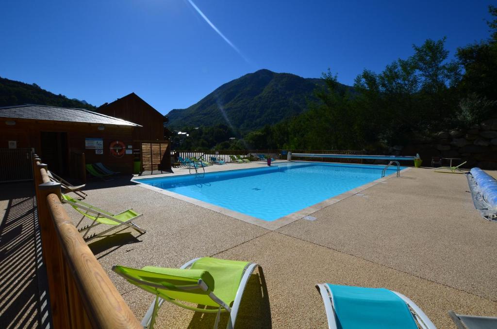 a swimming pool with chairs and a mountain in the background at Les Reflets d'Ax in Ax-les-Thermes