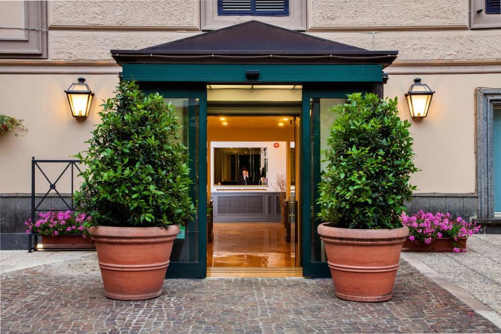 zwei große Topfpflanzen vor einem Gebäude in der Unterkunft Hotel Buenos Aires in Rom