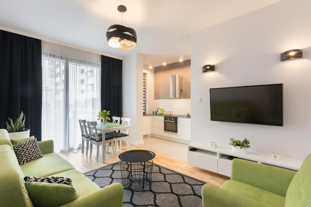 a living room with a couch and a tv at Millennium Awangarda Green in Warsaw