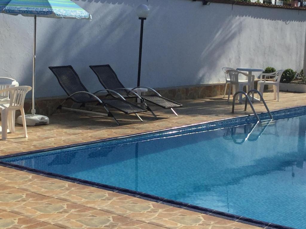 una piscina con sedie, tavoli e ombrellone di Vila do Tombo a Guarujá