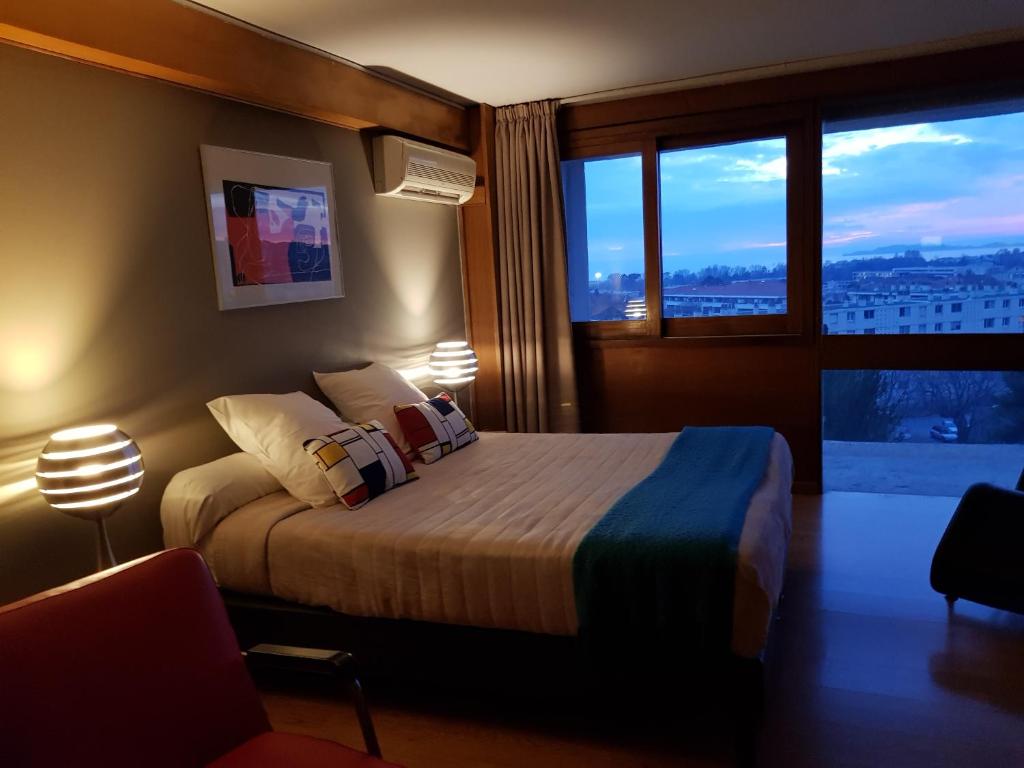 a bedroom with a bed and a large window at Hotel le Corbusier in Marseille