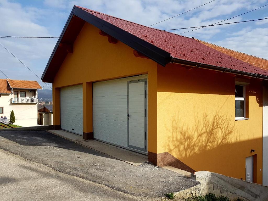 een geel en oranje huis met een garage bij Apartment Benjo in Sarajevo