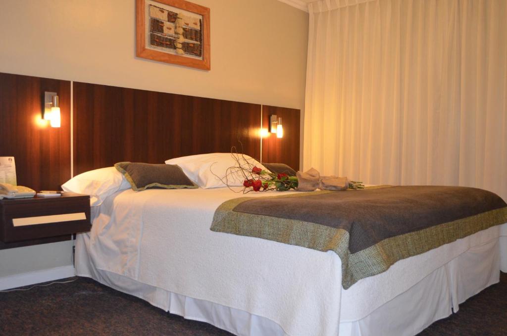 a hotel room with a large bed with flowers on it at Hotel Don Eduardo in Temuco