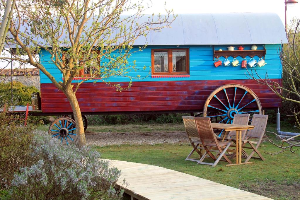 einem blauen und roten Wohnwagen mit einem Tisch und Stühlen in der Unterkunft Roulotte "Grain de Folie" in Waben