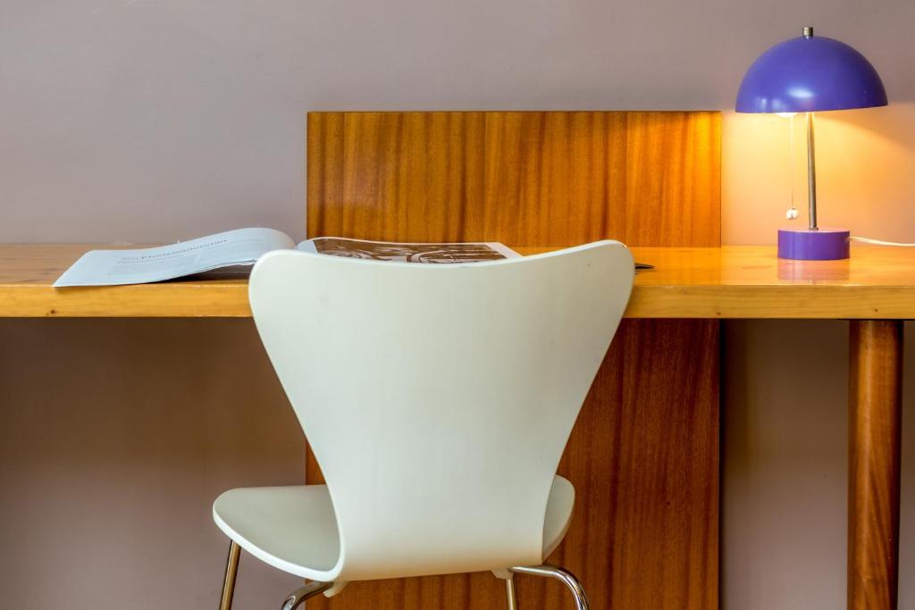 a desk with a white chair and a blue lamp at Hotel le Corbusier in Marseille