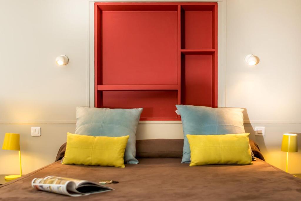 a bedroom with a red headboard and two yellow pillows at Hotel le Corbusier in Marseille