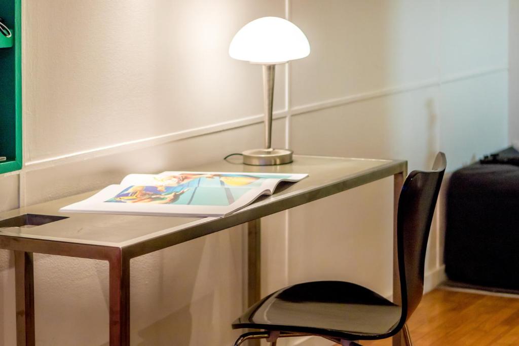 a desk with a lamp and a book and a chair at Hotel le Corbusier in Marseille