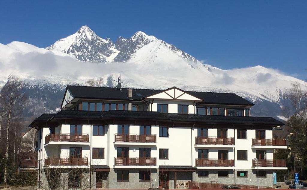 un bâtiment avec une montagne enneigée en arrière-plan dans l'établissement Apartmán Lomnička - Tatranská Lomnica, à Tatranská Lomnica