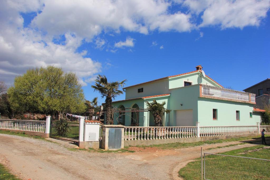 uma casa com uma cerca branca ao lado de uma estrada de terra em Radeki polje 50 em Loborika